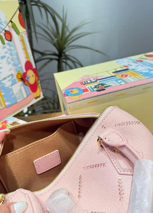 Mini borsa in pelle martellata rosa chiaro con cuciture trapuntate, chiusura con cerniera a lucchetto e tracolla rimovibile con catena dorata.
